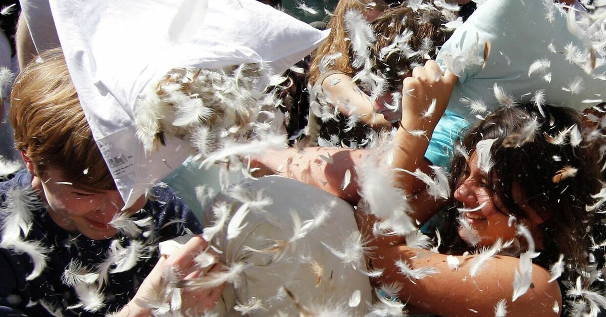 Фотосессия с подушками. Дерутся подушками. Драка подушками дети. Фотосессия бой подушками. Парень и девушка дурачатся.