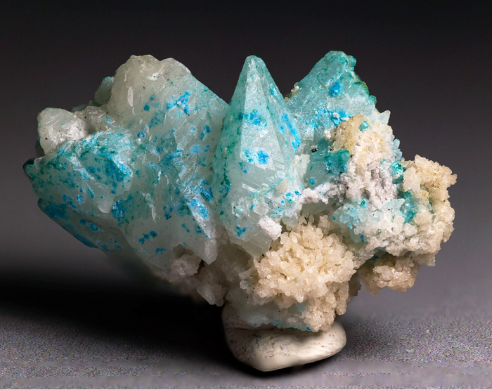 Скаленоэдры кальцита, покрытые плёнками и радиально-лучистыми агрегатами серпиерита. В ассоциации присутствуют зелёные плёнки малахита. Фотография Бадьяновой Л.В. Размер образца 3 х 2 х 2 см.