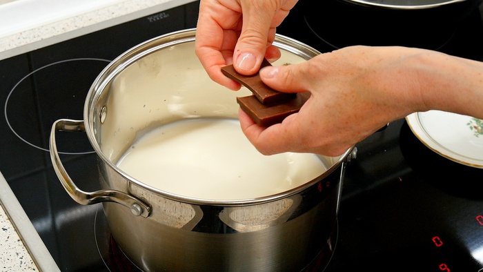 600-800 миллилитров молока ставим на сильный огонь. Молоко можно взять кокосовое: оптимально 6% жирности. Если жирнее, то лучше разбавить водой.
Одну стограммовую плитку молочного шоколада ломаем на квадратики и закидываем в нагревающееся молоко.