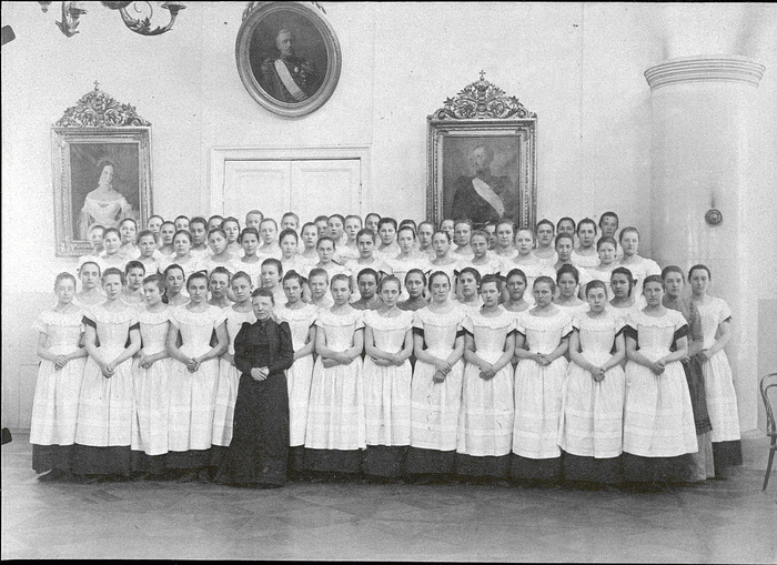 Группа институток в открытых белых фартуках.