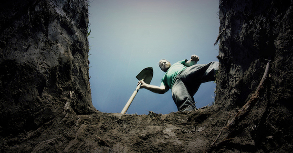 Сверху кидать. Человек роет яму.