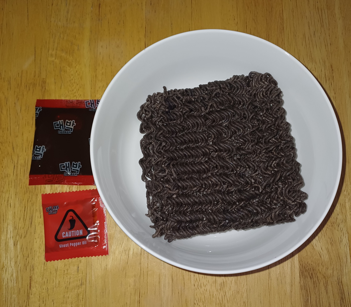 Лапшу красили, то ли концентрированным морковным соком, то ли порошком какао. На упаковке конкретно не указан краситель. В пакетике побольше - вкусный соус, как в Булдаках, немного острый. Который поменьше - масло перца-призрака.