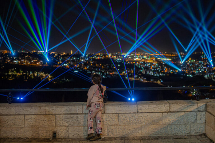 Молодая девушка смотрит на лазерное шоу в Иерусалиме. Изображение Дора Пасуэло.
